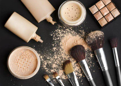 a collection of beige colored makeup in bottles, powders, and so on, along with makeup brushes to apply it