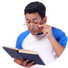 a man adjusting his reading glasses as he reads a book