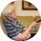 elderly woman pointing a remote at an off-screen tv