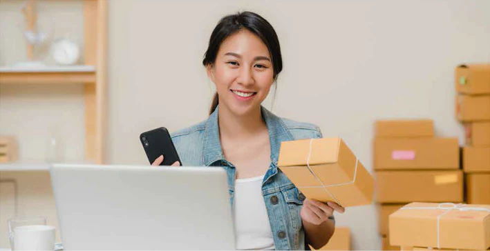 Woman with her phone with one hand and a box in her other